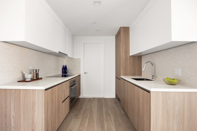 kitchen with white cabinetry, light hardwood / wood-style floors, sink, oven, and black electric cooktop