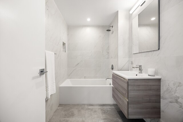 bathroom featuring tile walls, vanity, and shower / bathing tub combination