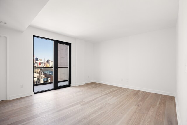 spare room featuring french doors and light hardwood / wood-style flooring