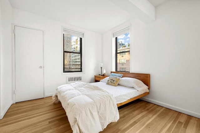 bedroom featuring hardwood / wood-style floors and beam ceiling