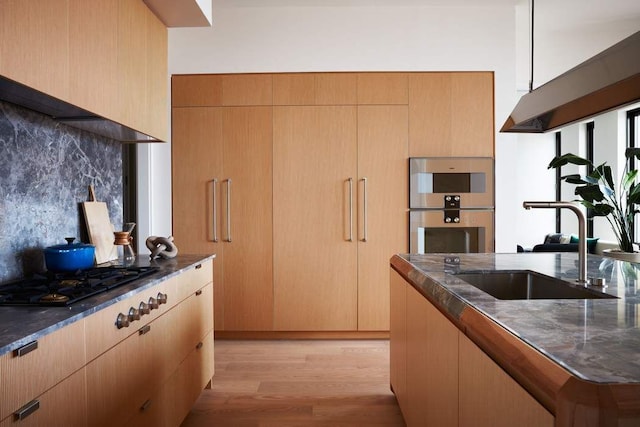 kitchen with sink, gas cooktop, light hardwood / wood-style floors, decorative backsplash, and stainless steel double oven