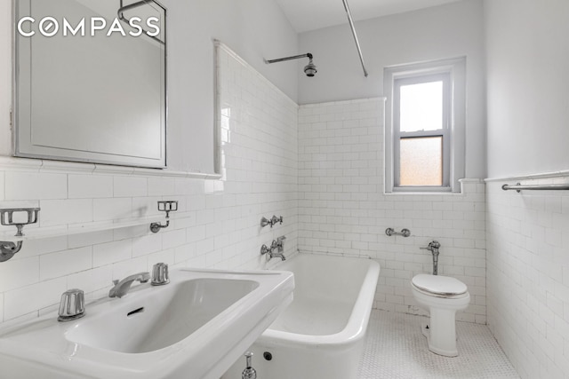 full bathroom featuring a tub to relax in, tile walls, toilet, a sink, and tile patterned flooring