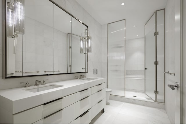 bathroom featuring a shower stall, toilet, double vanity, and a sink