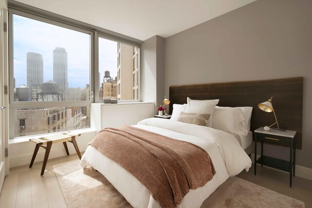 bedroom featuring baseboards, a city view, and wood finished floors