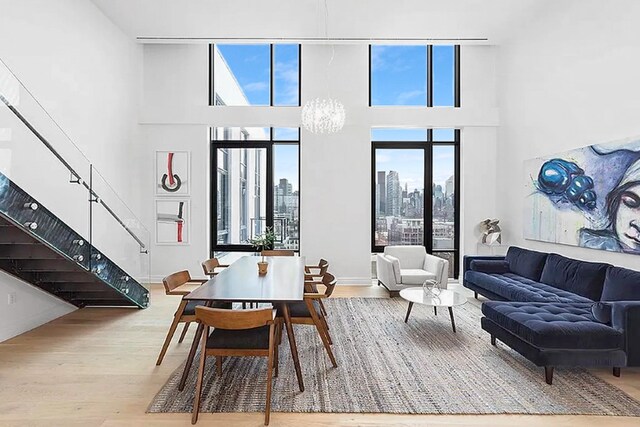 dining area with stairway, wood finished floors, a towering ceiling, an inviting chandelier, and a view of city