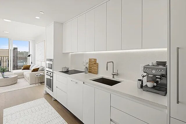 kitchen with sink, white cabinetry, dark hardwood / wood-style floors, black electric stovetop, and stainless steel oven