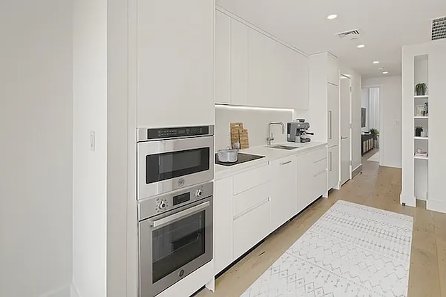 kitchen featuring wall oven, visible vents, white cabinets, oven, and light countertops