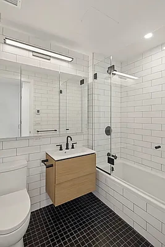 full bath with toilet, tiled shower / bath combo, tile patterned flooring, vanity, and tile walls