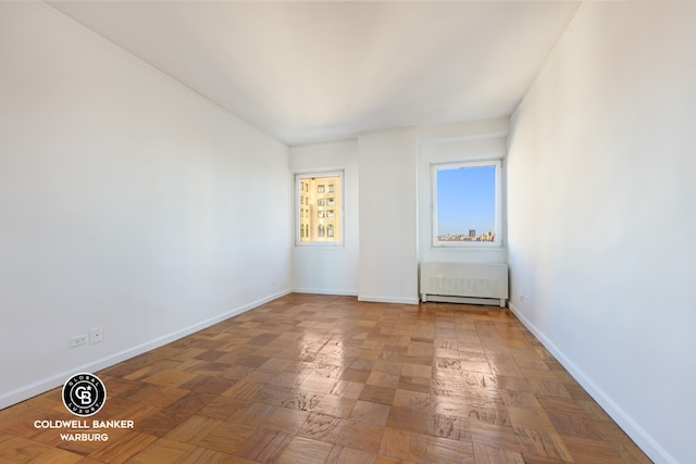 empty room featuring parquet floors and radiator heating unit