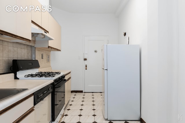 kitchen featuring light countertops, freestanding refrigerator, white cabinetry, gas range, and under cabinet range hood