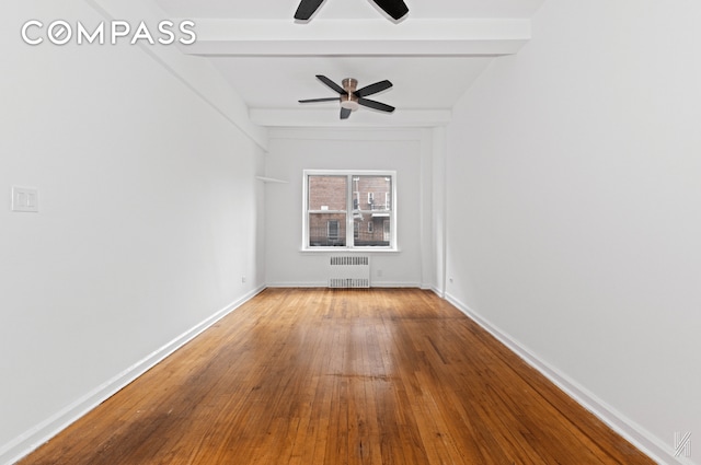 spare room with radiator, baseboards, beam ceiling, and wood finished floors