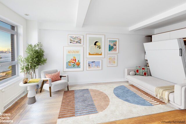 sitting room with a baseboard radiator, light hardwood / wood-style flooring, and beamed ceiling