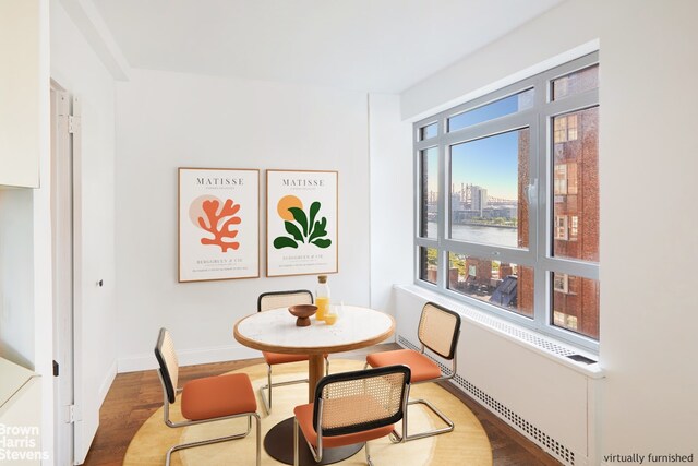 dining space with a city view, baseboards, and wood finished floors