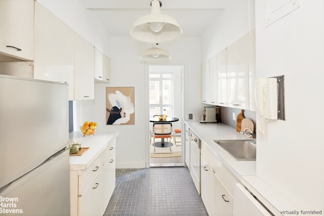 2 Beekman Pl Unit 10B, New York City, NY 10022 - kitchen with freestanding refrigerator, a sink, light countertops, and white cabinets