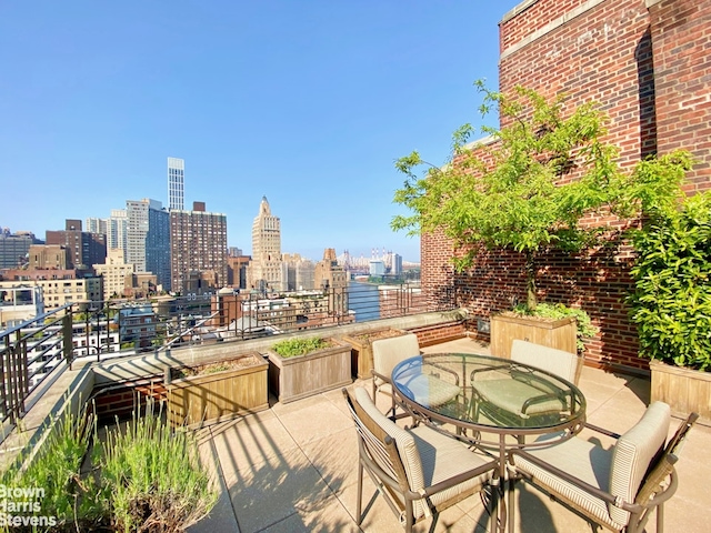 view of patio with a city view, outdoor dining area, and a balcony