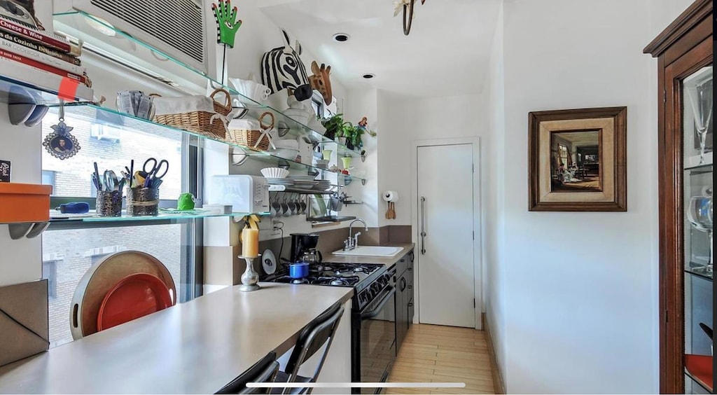 269 W 72nd St Unit 16D, New York City, NY 10023 - kitchen with gas stove, a sink, light wood-type flooring, and baseboards