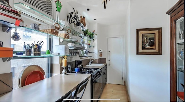 269 W 72nd St Unit 16D, New York City, NY 10023 - kitchen with gas stove, a sink, light wood-type flooring, and baseboards