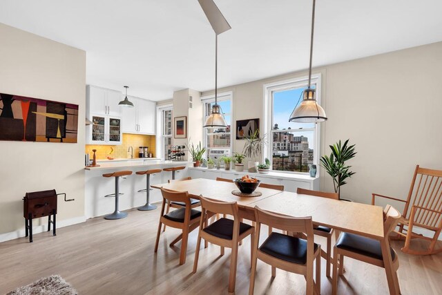 kitchen featuring white cabinetry, stainless steel appliances, decorative backsplash, decorative light fixtures, and wall chimney exhaust hood