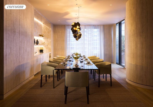 dining space featuring expansive windows, wood-type flooring, and wooden walls