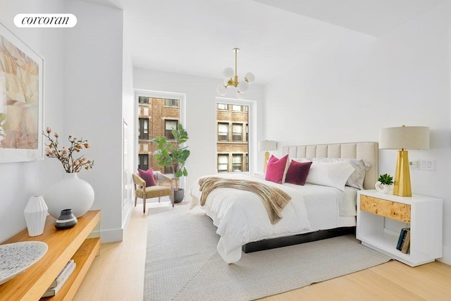 bedroom with a chandelier, vaulted ceiling, wood finished floors, and visible vents