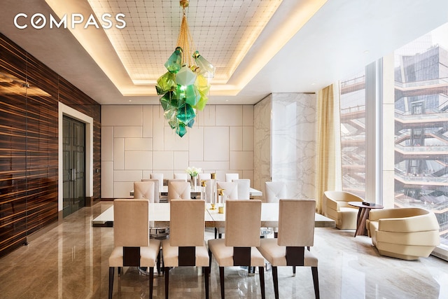 dining area featuring marble finish floor and a raised ceiling