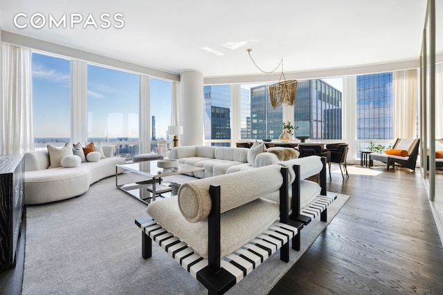 living area with a healthy amount of sunlight, an inviting chandelier, a city view, and wood finished floors