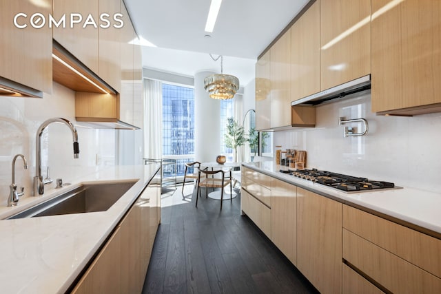 kitchen with modern cabinets, stainless steel gas cooktop, dark wood-style flooring, and a sink