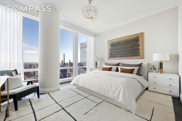 bedroom with an inviting chandelier, a city view, and wood finished floors