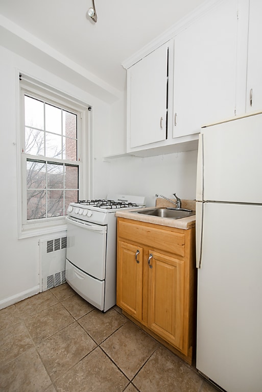 clothes washing area featuring sink, radiator heating unit, and light tile patterned floors