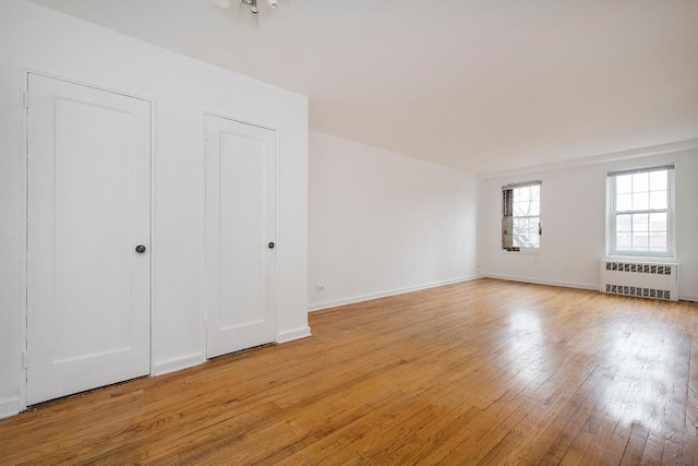 unfurnished room featuring radiator heating unit and light wood-type flooring