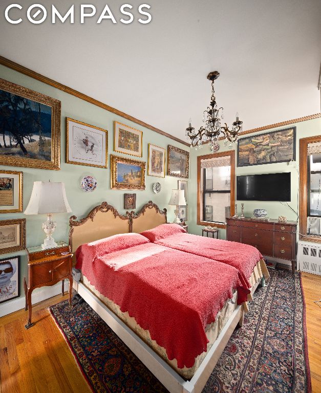 bedroom with hardwood / wood-style floors, crown molding, and a chandelier