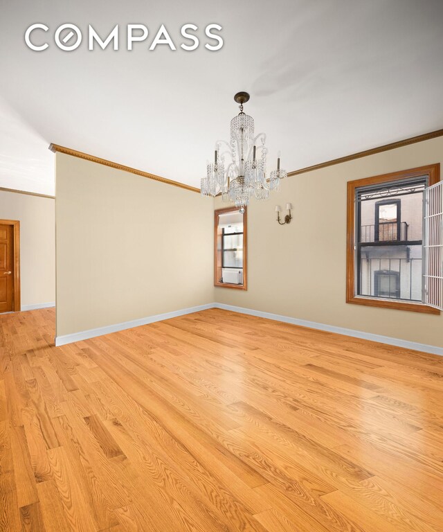 empty room featuring light wood-type flooring, crown molding, and a chandelier