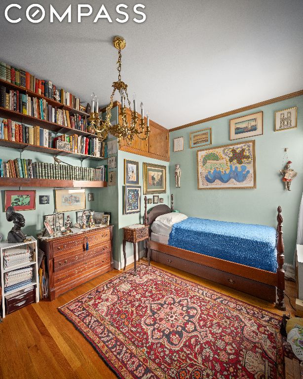 bedroom featuring hardwood / wood-style flooring, crown molding, and a chandelier