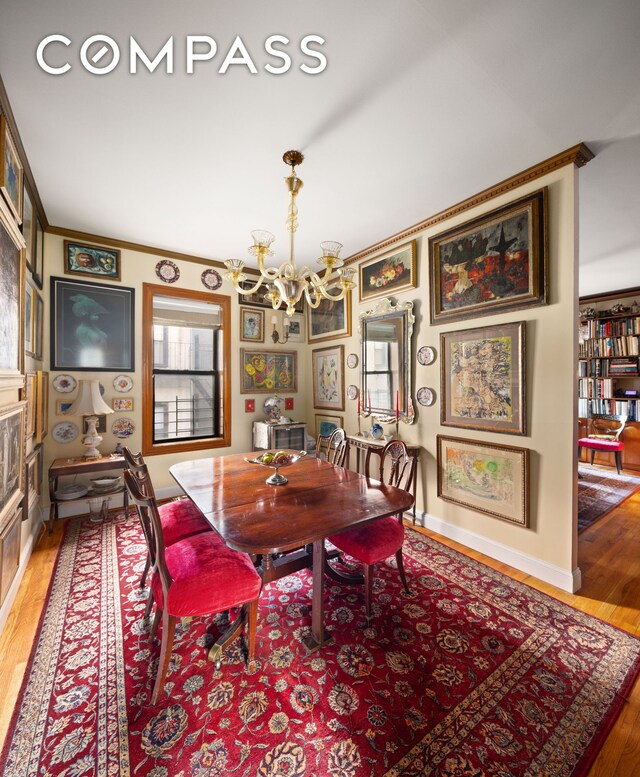 dining room featuring a healthy amount of sunlight, light hardwood / wood-style flooring, ornamental molding, and an inviting chandelier