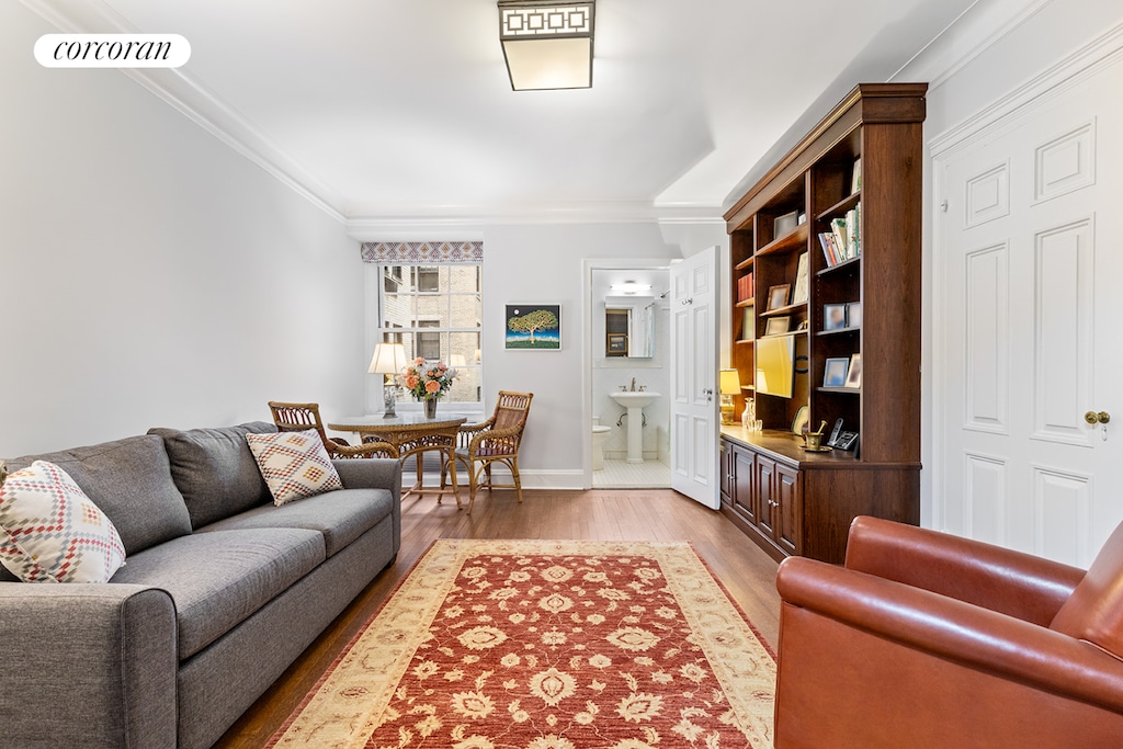 living room with light wood-type flooring, ornamental molding, and baseboards