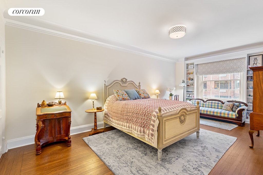 bedroom featuring crown molding, hardwood / wood-style floors, and baseboards
