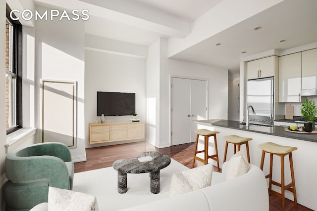 living room with sink, dark wood-type flooring, and beamed ceiling