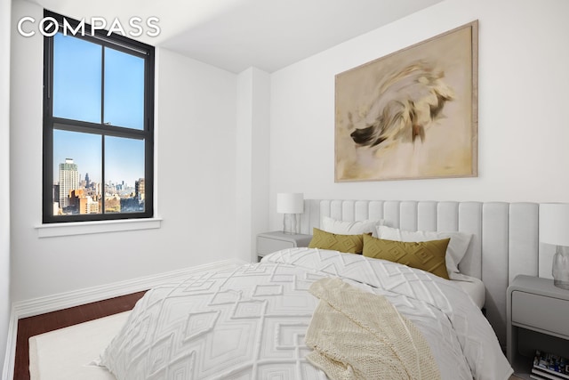 bedroom featuring a city view, wood finished floors, and baseboards