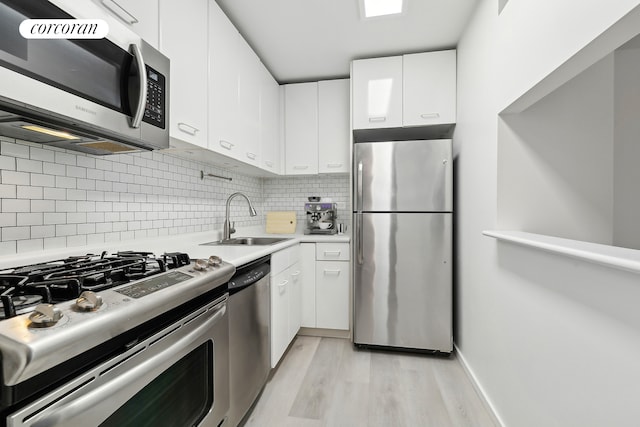 kitchen with appliances with stainless steel finishes, a sink, and white cabinetry