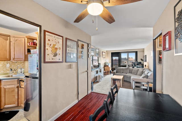 dining space with wood finished floors, a ceiling fan, and baseboards