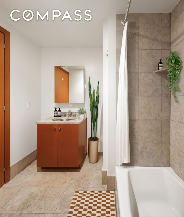 bathroom featuring tile patterned floors, baseboards, shower / bath combo with shower curtain, and vanity