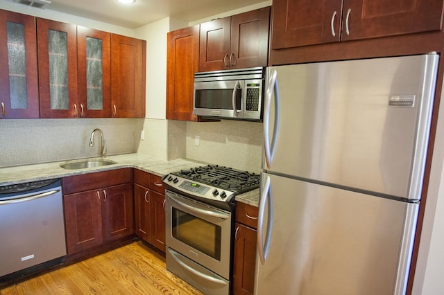 712 6th Ave Unit 4, New York City, NY 11215 - kitchen featuring appliances with stainless steel finishes, a sink, light stone counters, light wood-style flooring, and glass insert cabinets