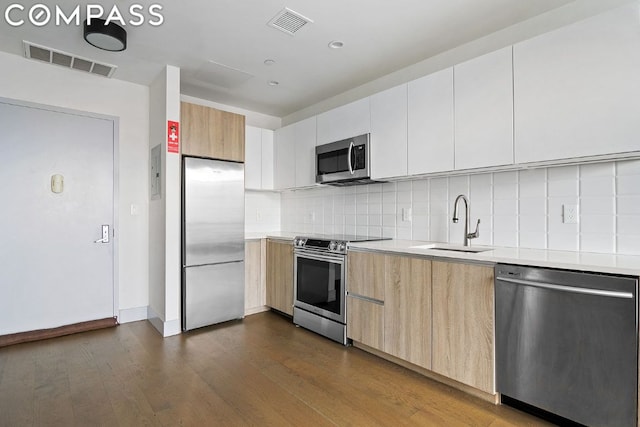 kitchen with dark wood-type flooring, stainless steel appliances, white cabinets, and sink