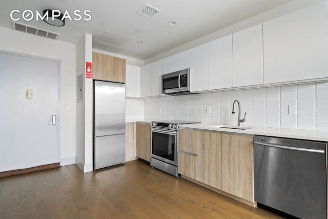 kitchen with sink, stainless steel appliances, dark hardwood / wood-style floors, white cabinets, and decorative backsplash