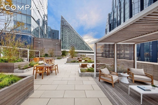 view of patio / terrace with a view of city, outdoor dining area, and a vegetable garden