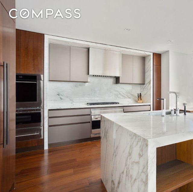 kitchen featuring tasteful backsplash, sink, stainless steel appliances, dark wood-type flooring, and wall chimney exhaust hood