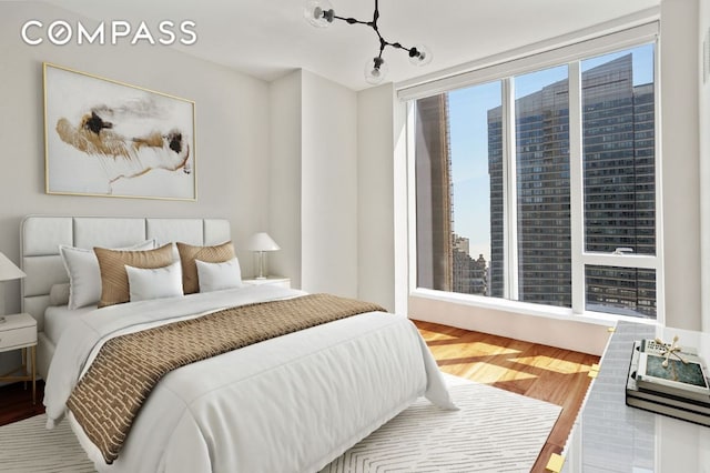 bedroom with a view of city and wood finished floors