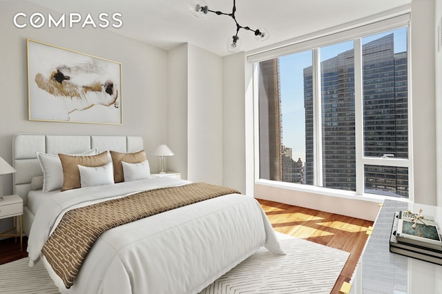 bedroom featuring a view of city and wood finished floors