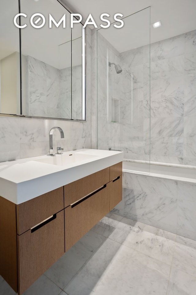 full bathroom with marble finish floor, tile walls, a combined bath / shower with marble appearance, and vanity