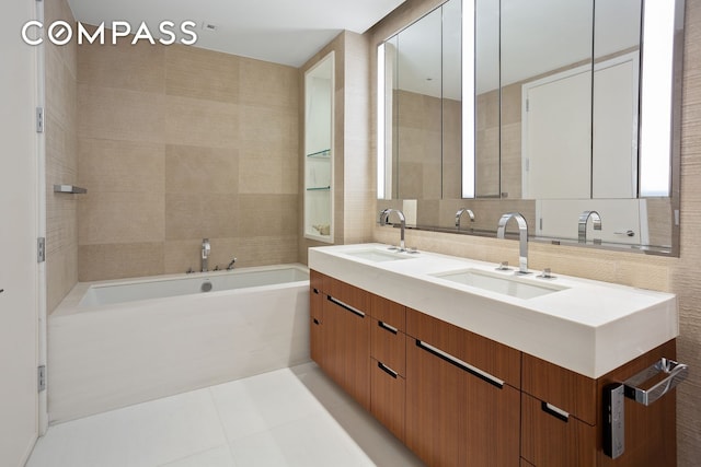 bathroom featuring a bath, double vanity, a sink, and tile walls